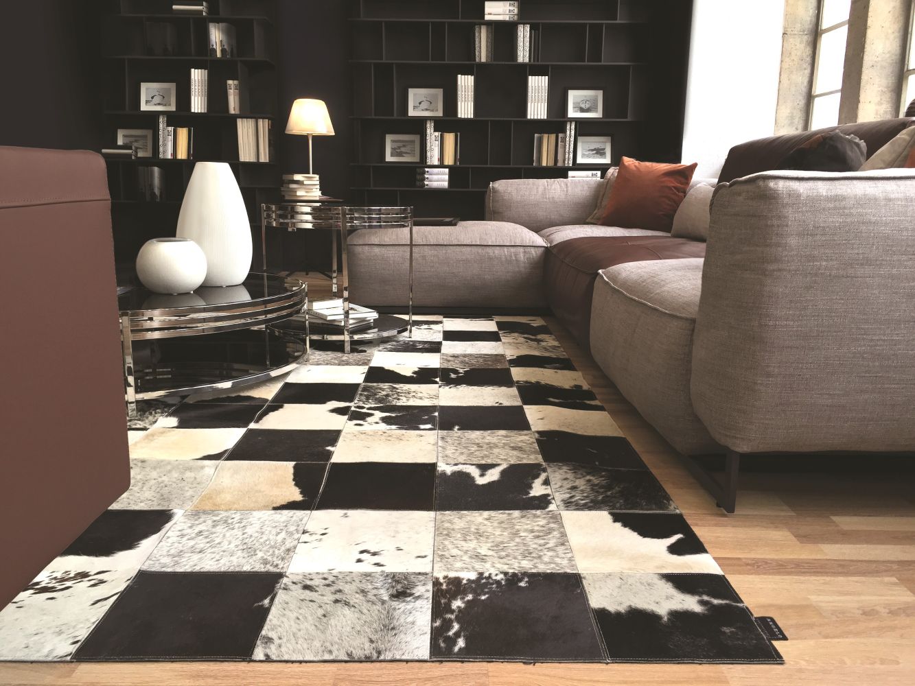 Tapis en cuir de vachette damier gris ivoire noir intégré dans un salon moderne, ambiance chaleureuse